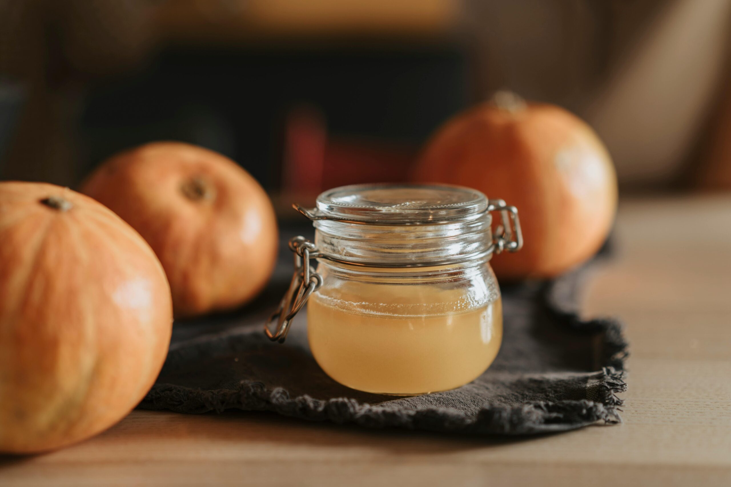 pexels photo 5471920 5471920 A cozy still life with homemade apple cider in a glass jar surrounded by pumpkins on a wooden table.