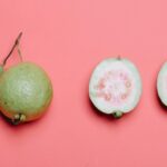 Whole and cut guava with leaf on pink background. Perfect for healthy eating concepts.